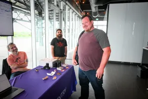 A guest smiling with Sentry representatives at their sponsor booth.