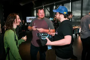 A group of guests chatting while eating, drinking, and holding their apparel.