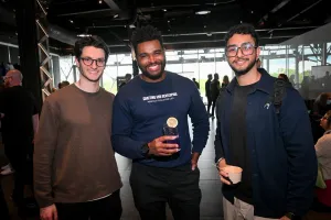 Guests posing together and smiling at the camera while holding drinks.