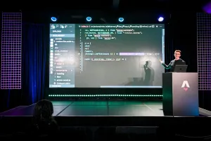 Ben Holmes on stage at the podium, sharing a demo. He is live-coding.