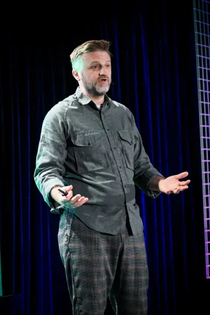 Portrait shot of Matthew Phillips speaking on stage.