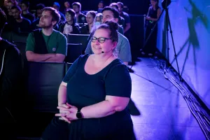 Sarah Rainsberger, another keynote speaker, smiles off-stage while watching Matthew Phillips speak on stage.