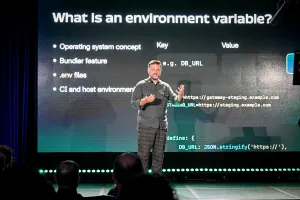 Matthew Phillips speaking on stage, explaining what an environment variable is.