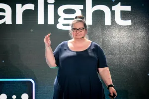 Closeup of Sarah Rainsberger speaking on stage in front of the Starlight logo.