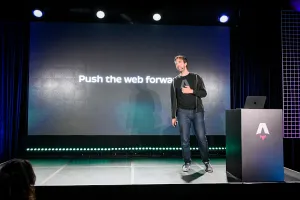 Fred K. Schott speaking on stage next to an Astro-branded podium, in front of a slide that reads, "Push the web forward".