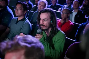 An audience member holding a microphone, asking keynote speakers a question.