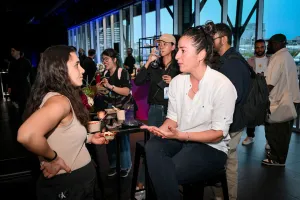 Guests chatting with one another while they eat their food sitting at high tables.