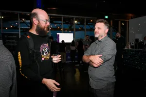 Matthew Phillips chatting with a guest. It is now so dark that the rest of the guests are hard to see and you do not see much outside the window.